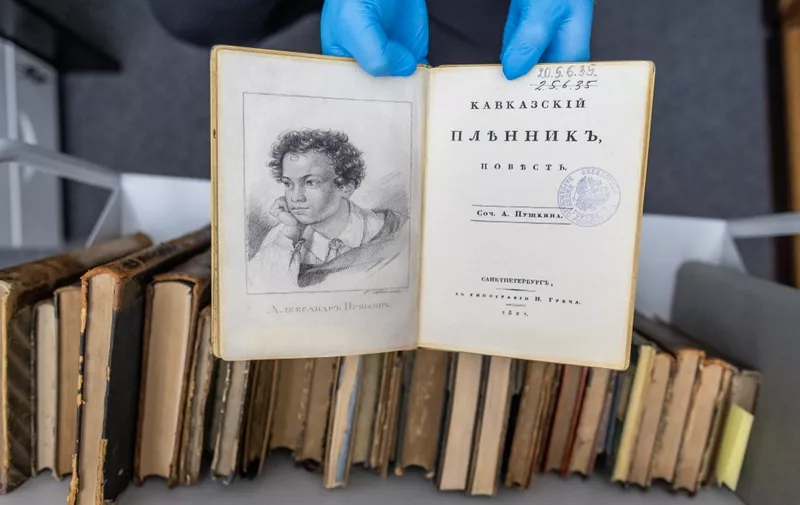 A university employee presents a fake copy of a first edition of the 1822 book 'Kavkazskiy plennik: povest' by Alexander Pushkin at the University of Warsaw library in Warsaw, Poland on November 14, 2023. A spate of thefts of rare Russian classics worth millions of euros from libraries across Eastern Europe has left a trail that points all the way to Moscow. (Photo by Wojtek Radwanski / AFP)
