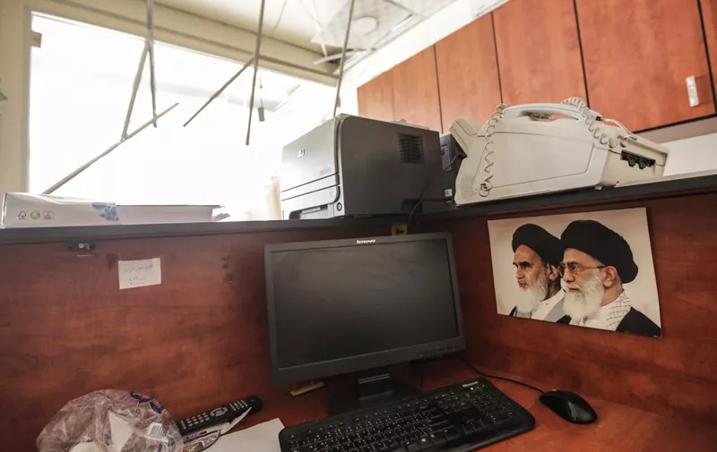 This picture taken on August 25, 2019 shows damage inside a media centre of the Lebanese Shiite group Hezbollah in the south of the capital Beirut, after two drones came down in the vicinity of its building earlier in the day, with (L to R) pictures of Iran's former and current Supreme Leaders, Ayatollah Ruhollah Khomeini and Ayatollah Ali Khamenei, seen next to a computer terminal. - Hezbollah said on August 25 that one of the drones was rigged with explosives and caused damage to its media centre, but denied shooting down any of them. The early morning incident came hours after Israel launched air strikes in neighbouring Syria, but Hezbollah officials could not confirm if the drones deployed in Lebanon were Israeli. Another Hezbollah source told AFP the Iran-backed Shiite militant group -- a major political player in Lebanon with representatives in parliament and the government -- has not determined if the drones were Israeli. (Photo by ANWAR AMRO / AFP)