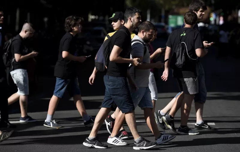 Gamers use the Pokemon Go application on their mobile phones while walking in Barcelona, on July 14, 2016.  / AFP PHOTO / JOSEP LAGO