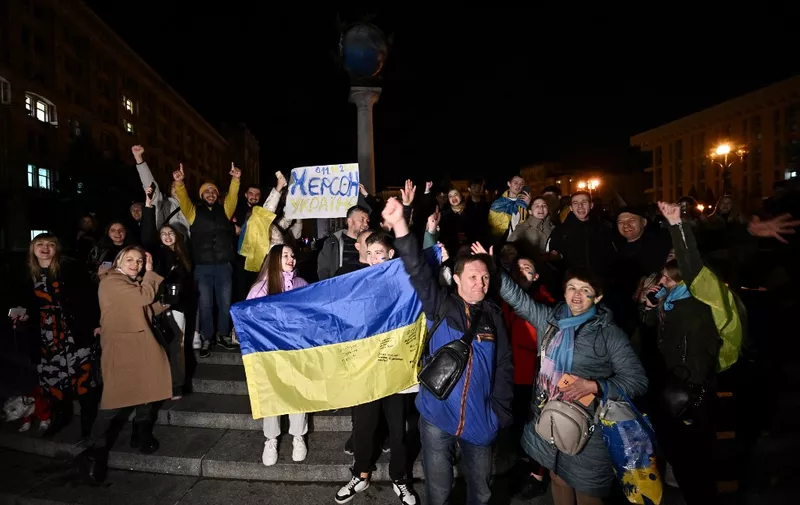 People hold a Ukranian flag and a slogan which reads as "11/11/2022 - Kherson - Ukraine" as they gather in Maidan Square to celebrate the liberation of Kherson, in Kyiv on November 11, 2022, amid the Russian invasion of Ukraine. - Ukraine's President Volodymyr Zelensky said on November 11 that Kherson was "ours" after Russia announced the completion of its withdrawal from the regional capital, the only one Moscow captured in nearly nine months of fighting. (Photo by Genya SAVILOV / AFP)
