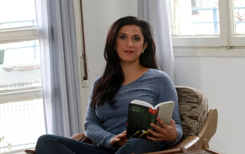 Israeli author Dorit Rabinyan poses with her Hebrew-language novel titled "Gader Haya" (known in English as "Borderlife") on December 31, 2015 at her house in the coastal city of Tel Aviv. Israels Education Ministry Naftali Bennett has disqualified Rabinyan's novel, that describes a love story between an Israeli woman and a Palestinian man, for use in advanced literature classes in Israeli high schools.  
AFP PHOTO/ GIL COHEN-MAGEN / AFP / GIL COHEN MAGEN