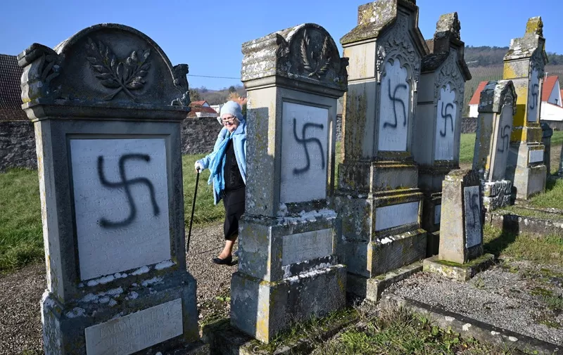 A woman walks by vandalised tombs, on December 4, 2019 at the jewish  cemetery of Westhoffen near Strasbourg, eastern France, where 107 graves were found vandalised with swastikas and antisemitic inscriptions. (Photo by PATRICK HERTZOG / AFP)