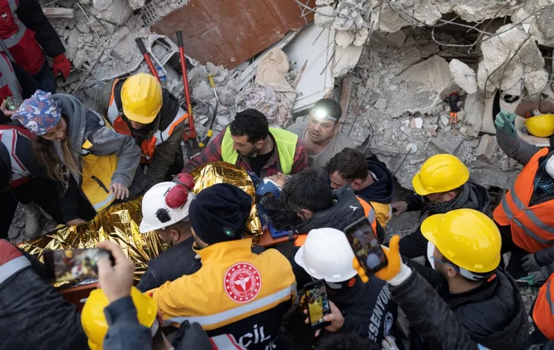 A woman saved by rescue workers is carried to an ambulance, five days following two massive back-to-back earthquakes that struck both Turkey and Syria, in Hatay, southern Turkey on February 10, 2023. - Rescuers pulled out children on February 10, 2023, from the rubble of the Turkey-Syria earthquake that struck on February 6, 2023, as the toll approached 23,000 and a winter freeze compounded the suffering for nearly one million people estimated to be in urgent need of food. (Photo by BULENT KILIC / AFP)