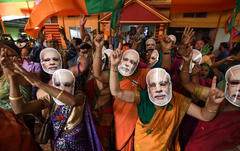 Indian Bharatiya Janata Party (BJP) supporters wearing masks of Indian Prime Minister Narendra Modi dance as they celebrate on the vote results day for India's general election at BJP office in Guwahati on May 23, 2019. - Indian Prime Minister Narendra Modi looked on course on May 23 for a major victory in the world's biggest election, with early trends suggesting his Hindu nationalist party will win a bigger majority even than 2014. (Photo by Biju BORO / AFP)