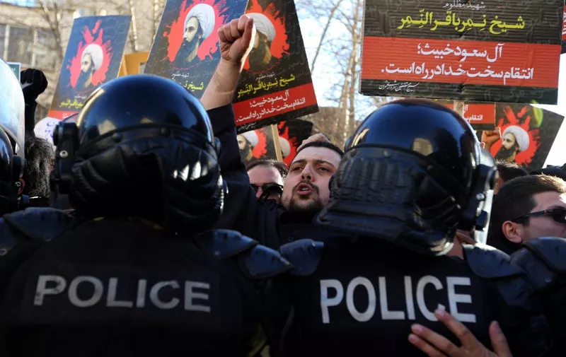 Iranian protesters hold portraits of prominent Shiite Muslim cleric Nimr al-Nimr as they confront riot police during a demonstration against his execution by Saudi authorities, on January 3, 2016, outside the Saudi embassy in Tehran. Iran and Iraq's top Shiite leaders condemned Saudi Arabia's execution of Nimr, warning ahead of protests that the killing was an injustice that could have serious consequences. AFP PHOTO / ATTA KENARE (Photo by ATTA KENARE / AFP)