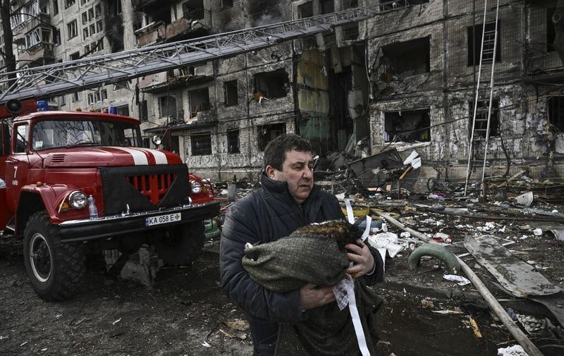 A man holds his dead cat in a blanket as he stands outside a destroyed apartment building after it was shelled in the northwestern Obolon district of Kyiv on March 14, 2022. - Two people were killed on March 14, 2022, as various neighbourhoods of the Ukraine capital Kyiv came under shelling and missile attacks, city officials said, after the Russia's military invaded the Ukraine on February 24, 2022. (Photo by Aris Messinis / AFP)