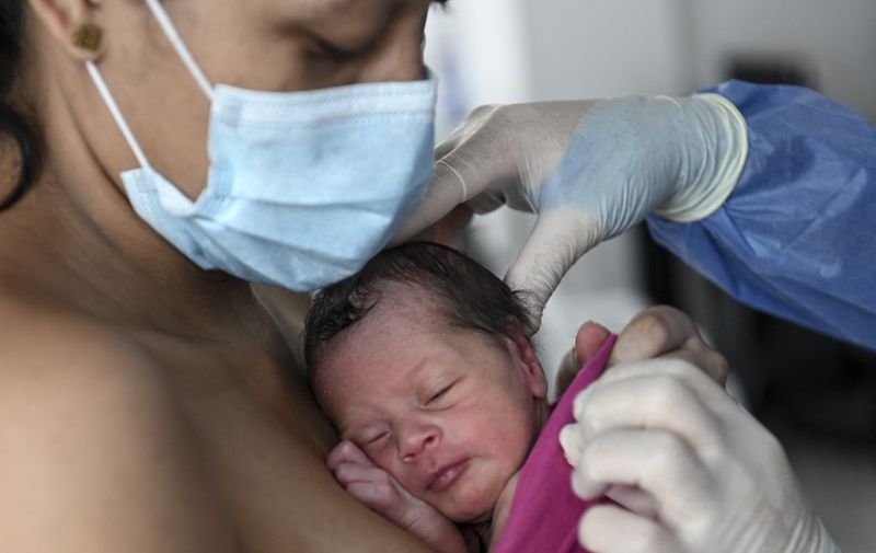 A mother carries her newly born baby as a doctor helps her during the novel coronavirus COVID-19 pandemic, at the post-natal lactation room at the Medellin General Hospital, in Medellin, Colombia, on May 21, 2020. (Photo by JOAQUIN SARMIENTO / AFP)