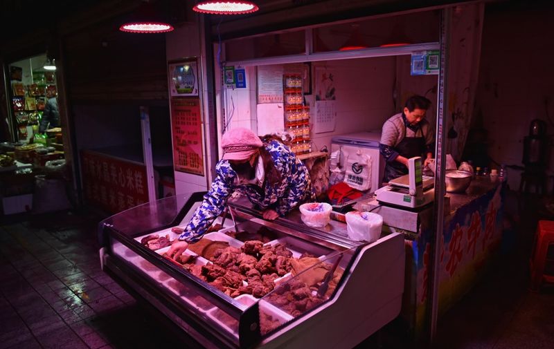 A vendor (C) wearing a facemask to help stop the spread of a deadly virus which began in the city offers meat at a near-empty market on the eve of the Lunar New Year in Wuhan on January 24, 2020, when normally markets would be bustling. - China sealed off millions more people near the epicentre of a virus outbreak on January 24, shutting down public transport in an eighth city in an unprecedented quarantine effort as the death toll from the disease climbed to 25. (Photo by HECTOR RETAMAL / AFP)