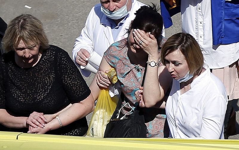 A woman cries as she is taken to an ambulance at the scene of a shooting at School No. 175 in Kazan, the capital of Russia's republic of Tatarstan, on May 11, 2021. (Photo by Roman Kruchinin / AFP)