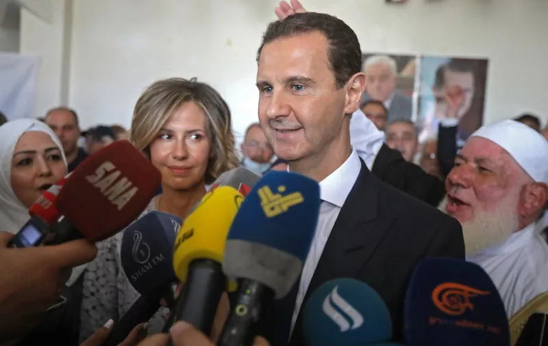 Syrian President Bashar al-Assad (R) accompanied by his wife Asma speaks to members of the press after casting their votes at a polling station in Douma, near the capital Damascus on May 26, 2021, as voting began across Syria for an election guaranteed to return Assad for a fourth term in office. - The 55-year-old president, who has been in power since 2000, is sure to keep his job after the election, every aspect of which is controlled by him and his Baath party. He faces former state minister Abdallah Salloum Abdallah and Mahmoud Merhi, a member of the so-called "tolerated opposition", long described by exiled opposition leaders as an extension of the regime. (Photo by LOUAI BESHARA / AFP)