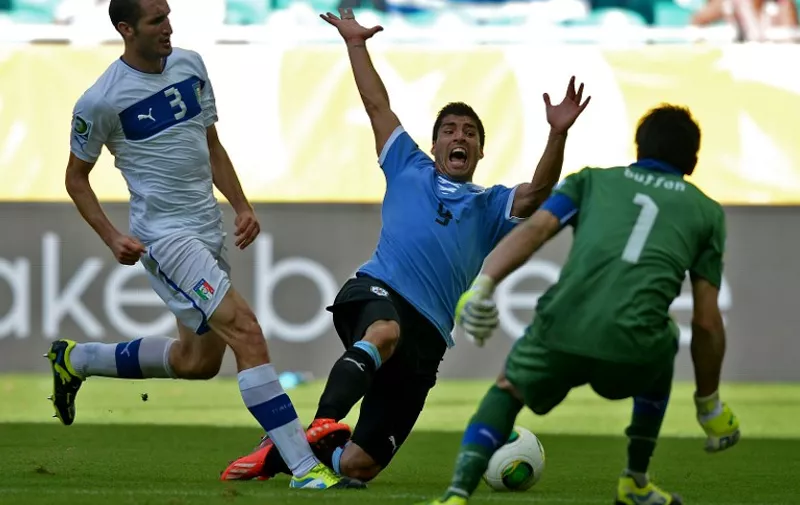 Uruguay's forward Luis Suarez (C) falls next to Italy's defender Giorgio Chielini and goalkeeper Gianluigi Buffon (R) during their FIFA Confederations Cup Brazil 2013 third-place football match, at the Fonte Nova Arena in Salvador, on June 30, 2013.   AFP PHOTO / 