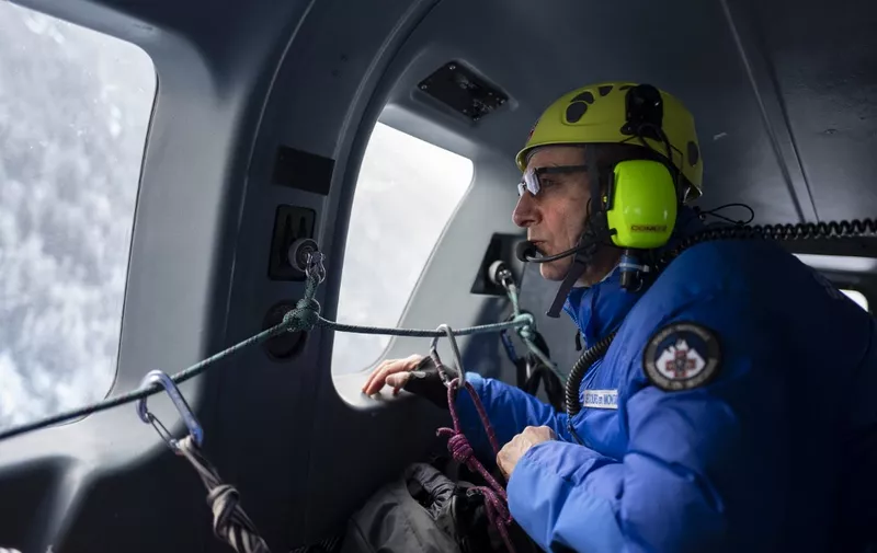 A CRS officer looks through a helicopter window during a final exam offering the avalanche dog handler degree on January 24, 2019, in the Prarion sector in Les Houches, central-eastern France. - The degree is delivered after a three weeks training in the CRS CNEAS (riot police's ski and alpinism national training center). Since four years, CNEAS pools training between CRS officer and Gendarmes. (Photo by ROMAIN LAFABREGUE / AFP)