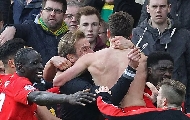 With his shirt off, Liverpool's English midfielder Adam Lallana celebrates scoring their late winning goal with Liverpool's German manager Jurgen Klopp (C) holding his glasses during the English Premier League football match between Norwich City and Liverpool at Carrow Road in Norwich, eastern England, on January 23, 2016. Liverpool won the game 5-4. AFP PHOTO / LINDSEY PARNABY

RESTRICTED TO EDITORIAL USE. No use with unauthorized audio, video, data, fixture lists, club/league logos or 'live' services. Online in-match use limited to 75 images, no video emulation. No use in betting, games or single club/league/player publications. / AFP / LINDSEY PARNABY