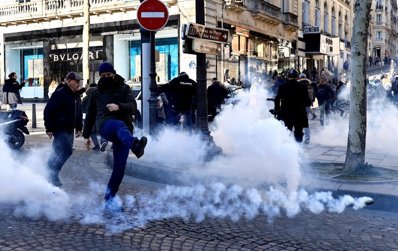 A man kicks a tear gas canister fired by French antiriot policemen on the Champs Elysees in Paris on February 12, 2022 as convoys of protesters so called "Convoi de la Liberte" arrived in the French capital. - Thousands of protesters in convoys, inspired by Canadian truckers paralysing border traffic with the US, were heading to Paris from across France on February 11, with some hoping to blockade the capital in opposition to Covid-19 restrictions despite police warnings to back off. The protesters include many anti-Covid vaccination activists, but also people protesting against fast-rising energy prices that they say are making it impossible for low-income families to make ends meet. (Photo by Sameer Al-DOUMY / AFP)