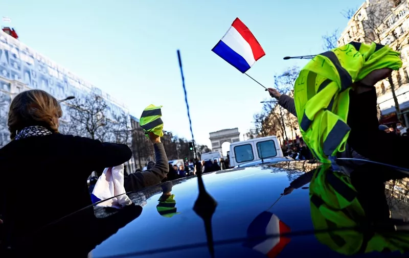 Demonstraters wave French flags and yellow vests on the Champs Elysees in Paris on February 12, 2022 as convoys of protesters so called "Convoi de la Liberte" arrived in the French capital. - Thousands of protesters in convoys, inspired by Canadian truckers paralysing border traffic with the US, were heading to Paris from across France on February 11, with some hoping to blockade the capital in opposition to Covid-19 restrictions despite police warnings to back off. The protesters include many anti-Covid vaccination activists, but also people protesting against fast-rising energy prices that they say are making it impossible for low-income families to make ends meet. (Photo by Sameer Al-DOUMY / AFP)