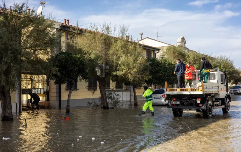 Men carry sand bags to stop water from flooding home basements in Marina di Pisa, Tuscany, on November 3, 2023 during the storm Ciaran. At least five people died in Tuscany, Italian authorities announced on Friday, reporting record rainfall and the declaration of a state of emergency. (Photo by Federico SCOPPA / AFP)