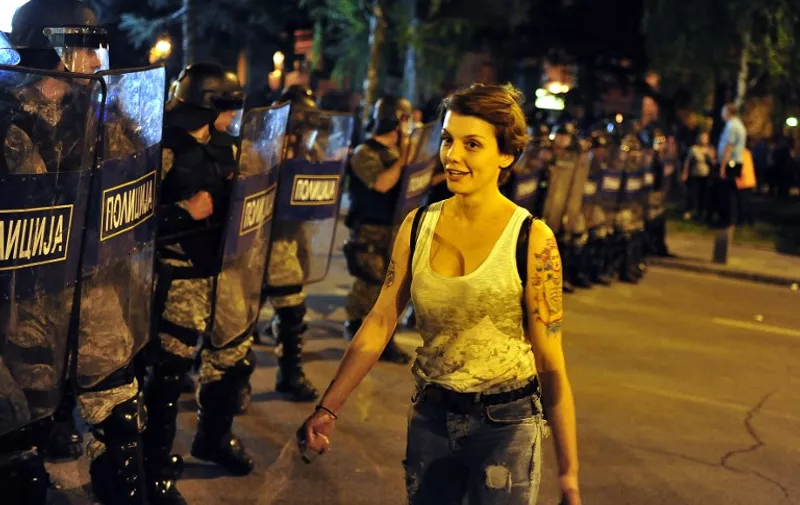 A young woman walk before a police cordon during a demonstration in Skopje on May 5, 2015.  Several thousand people protested outside the government building demanding the resignation of Prime Minister Nikola Gruevski, who was accused by the top opposition leader of trying to cover up the death of a 22-year-old who was beaten by a police member in 2011.   AFP  PHOTO / TOMISLAV GEORGIEV