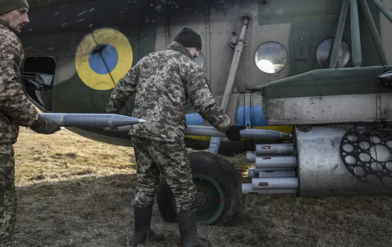 Ukrainian servicemen load rockets on a Mil Mi-8 helicopter in eastern Ukraine on March 10, 2023. (Photo by Aris Messinis / AFP)