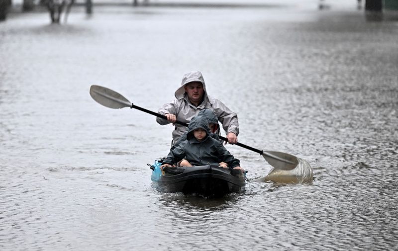People kayak along a flooded street from the overflowing Hawkesbury river due to torrential rain in the Windsor suburb of Sydney on July 4, 2022. (Photo by SAEED KHAN / AFP)