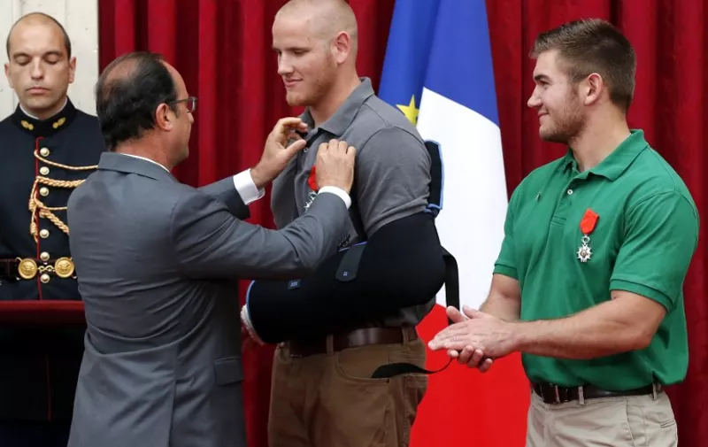 French President Francois Hollande (2nd L) awards France's top Legion d'Honneur medal to off-duty US serviceman Spencer Stone (2nd R), while with US serviceman Alek Skarlatos applauds during a reception at the Elysee Palace on August 24, 2015 in Paris, in recognition of their bravery, after they overpowered the Moroccan gunman in the train attack on August 21. AFP PHOTO / POOL / MICHEL EULER
