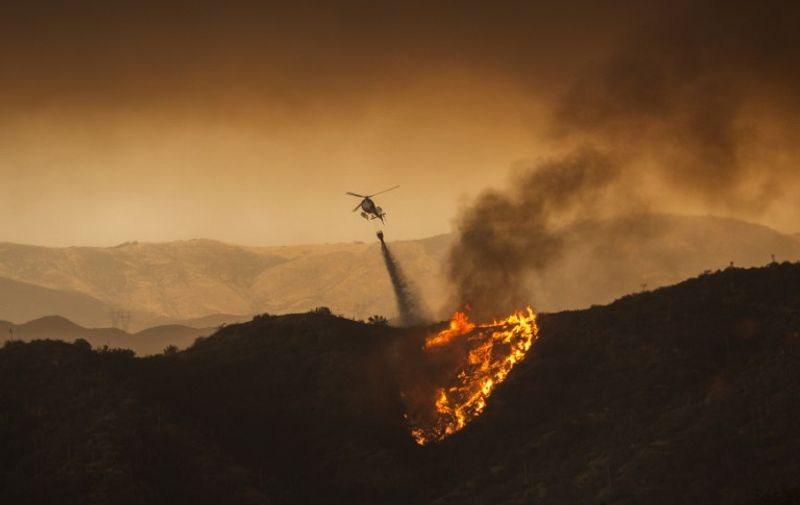 A firefighting helicopter drops water at the Sand Fire on July 23 2016 near Santa Clarita, California. 
Fueled by temperatures reaching about 108 degrees fahrenheit, the wildfire began yesterday has grown to 11,000 acres. / AFP PHOTO / DAVID MCNEW
