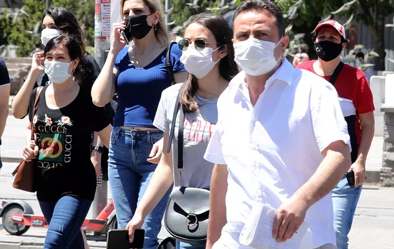 People wearing face masks as a protection against the coronavirus (Covid-19) walk in a street in Ankara on May 21, 21021. (Photo by Adem ALTAN / AFP)