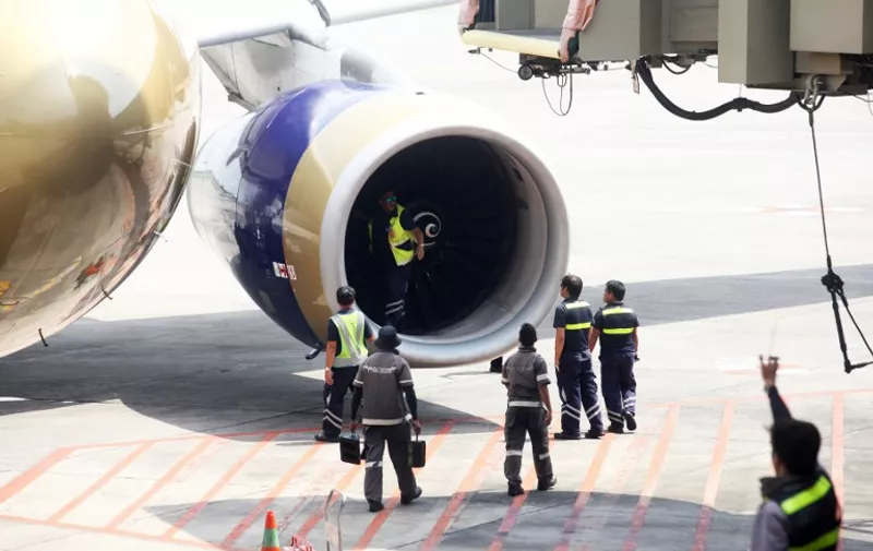 This photo taken on August 5, 2016 shows aircraft engineers inspecting one of the engines of an Airbus A330 of Gulf Air at the Manila international airport.  
The plane bound for Bahrain returned to Manila airport 25 minutes after taking off, due to engine trouble, according to authorities. / AFP PHOTO / STR