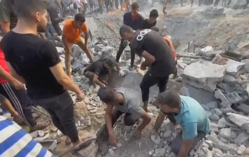 This image grab taken from AFPTV video footage shows Palestinians looking for survivors in a crater following a stike on a refugee camp in Jabalia on the northern Gaza Strip, on October 31, 2023, amid relentless Israeli bombardment of the Palestinian territory. The health ministry in the Hamas-run Gaza Strip said at least 50 people were killed on October 31 in Israeli bombardment of the refugee camp in the Palestinian territory. (Photo by Fadi Alwhidi / AFP) / The erroneous mention[s] appearing in the metadata of this photo by Fadi Alwhidi has been modified in AFP systems in the following manner: [northern Gaza] instead of [southern Gaza]. Please immediately remove the erroneous mention[s] from all your online services and delete it (them) from your servers. If you have been authorized by AFP to distribute it (them) to third parties, please ensure that the same actions are carried out by them. Failure to promptly comply with these instructions will entail liability on your part for any continued or post notification usage. Therefore we thank you very much for all your attention and prompt action. We are sorry for the inconvenience this notification may cause and remain at your disposal for any further information you may require.