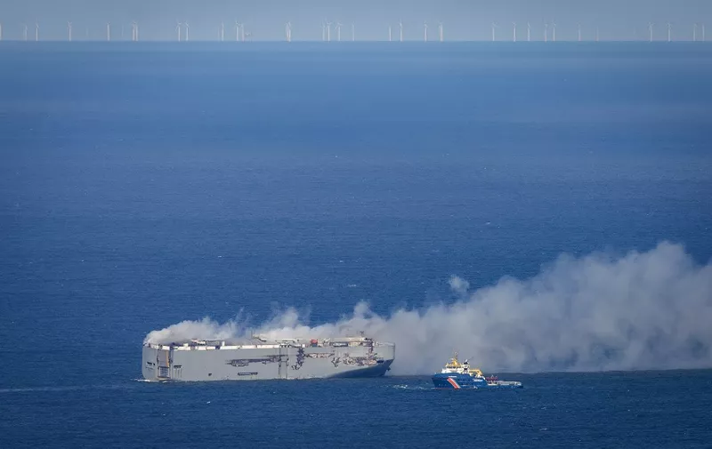 Dutch coastguard boat (R) approaches the Panamanian-registered car carrier cargo ship Fremantle Highway on fire off the coast of the northern Dutch island of Ameland, on July 26, 2023. One sailor died and several others were injured after a fire broke out on a car carrier ship off the Netherlands on July 26, the Dutch coastguard said. Rescue personnel received a call shortly after midnight (2200 GMT Tuesday) saying a fire had started on the Fremantle Highway, a Panamanian-registered ship with 3,000 vehicles on board, about 14.5 nautical miles (27 kilometres) off the northern Dutch island of Ameland. (Photo by Jan Spoelstra / ANP / AFP) / Netherlands OUT