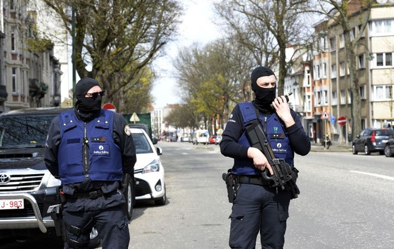 Belgian police officers stand guard in a street in Etterbeek while their colleagues search a warehouse in relation with terrorists arrests in Belgium, on April 09, 2016. 
A sixth person was arrested during raids on April 8, 2016 over the Brussels airport and metro bombings which netted top Paris attacks suspect Mohamed Abrini, the Belgian prosecutor's office said. / AFP PHOTO / THIERRY CHARLIER