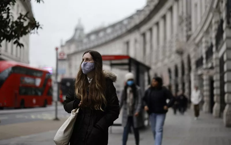 A woman wearing a face mask walks in London on January 21, 2022. - The UK government announced this week that restrictions reimposed in England last month to fight the surge in Omicron coronavirus cases would be lifted, citing data that showed infections had peaked. (Photo by Tolga Akmen / AFP)