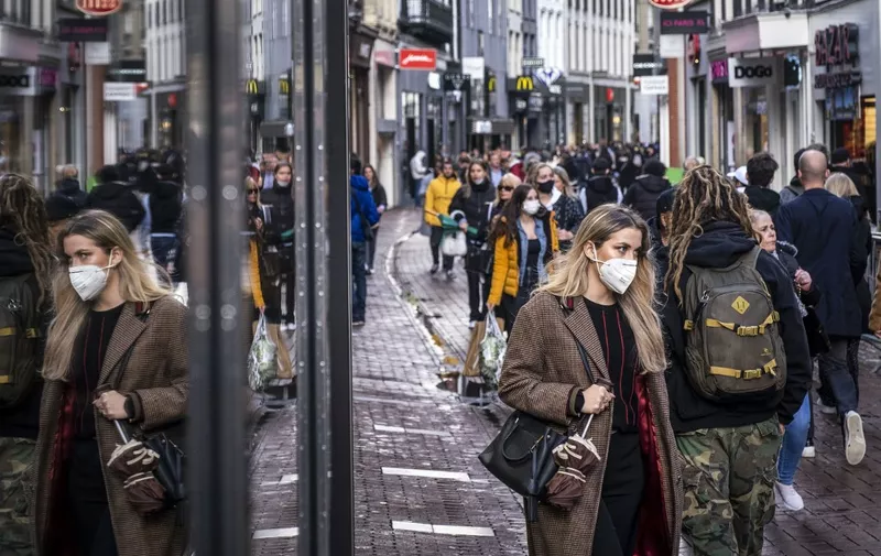 People wearing face masks walk on a shopping street in the center of Amsterdam on October 11, 2020. - The Dutch government is expected to take new measures to halt the spread the Covid-19 disease caused by the novel coronavirus. (Photo by Ramon van Flymen / ANP / AFP) / Netherlands OUT
