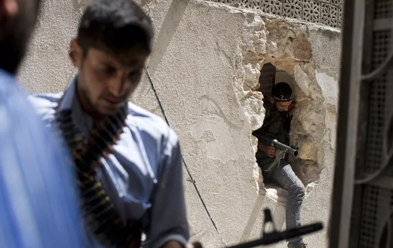 Members of the Katibat al-Ansar battalion of the Free Syrian Army move between buildings during clashes with forces loyal to President Bashar al-Assad in the Saif al-Dawla neighbourhood of Syria's northern city of Aleppo on August 21, 2012. At least 12 people were killed in a raid on a district of the capital, while fighter jets and artillery pummelled the northern city of Aleppo and rebels claimed seizing parts of a town on the Iraqi border, a watchdog said.  AFP PHOTO / ZAC BAILLIE / AFP PHOTO / ZAC BAILLIE