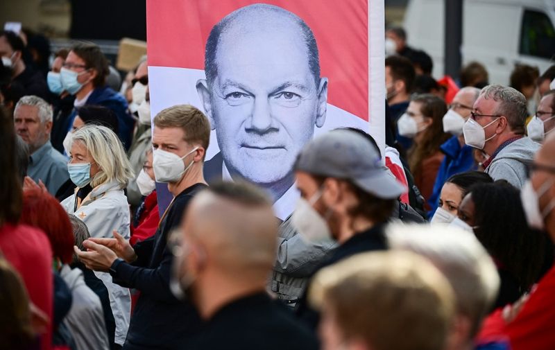 People hold up a banner of German Finance Minister, Vice-Chancellor and the Social Democrats (SPD) candidate for Chancellor Olaf Scholz during an election campaign event of the SPD in Berlin on August 27, 2021, ahead of general elections scheduled for September 26, 2021. (Photo by Tobias SCHWARZ / AFP)