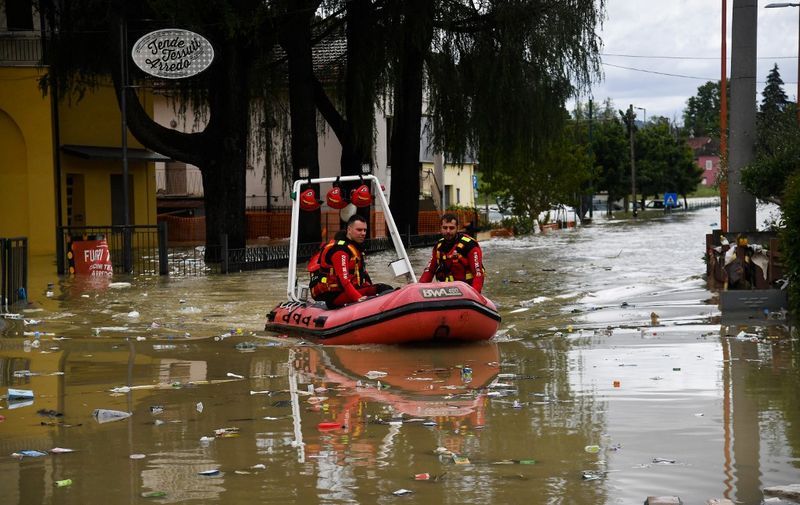 Volunteer firefighters ride their dinghy across a street flooded by the river Savio in the Ponte Vecchio district of Cesena, central eastern Italy, on May 17, 2023. Trains were stopped and schools were closed in many towns while people were asked to leave the ground floors of their homes and to avoid going out, and five people have died after the floodings across Italy's northern Emilia Romagna region. (Photo by Alessandro SERRANO / AFP)