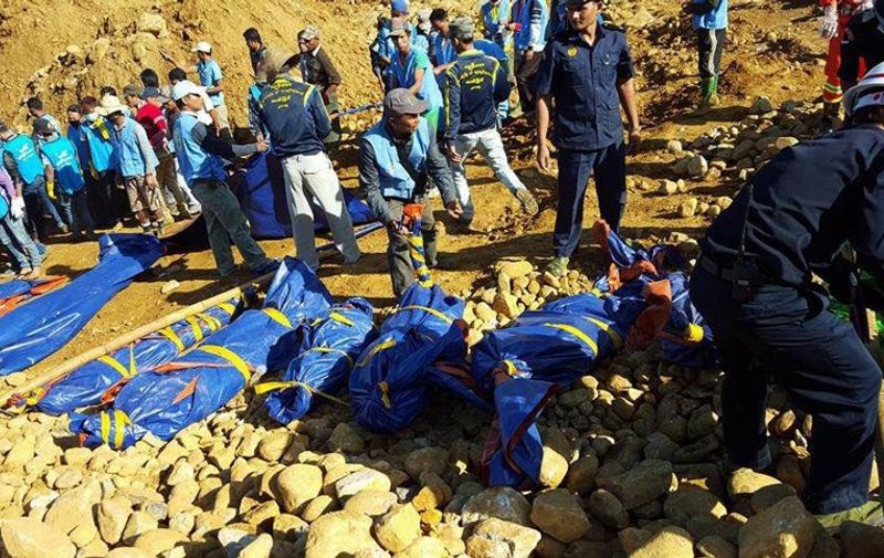 The bodies of miners killed by a landslide are placed on the ground in a jade mining area in Hpakhant, in Myanmar's Kachin state on November 22, 2015. At least 90 people have died in a huge landslide in a remote jade mining area of northern Myanmar, officials said on November 22, as search teams continued to find bodies in one of the deadliest disasters to strike the country's shadowy jade industry.  AFP PHOTO / AFP / STR