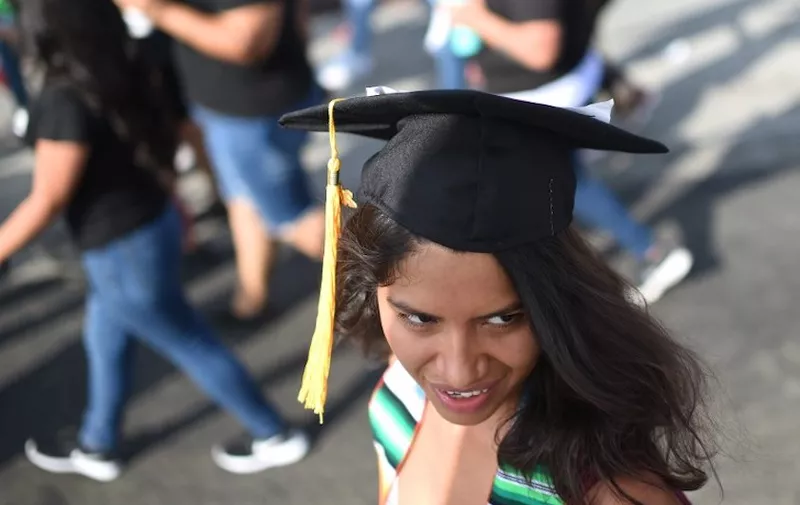 Pasadena City College graduate and DACA recipient Docnary Reyes, who plans to attend UC Davis in the fall, wears her graduation cap as she participates in a protest against efforts by the Trump administration to phase out DACA (Deferred Action for Childhood Arrivals) which provides protection from deportation for young immigrants brought into the US illegally by their parents, September 10, 2017 in Los Angeles, California. / AFP PHOTO / Robyn Beck