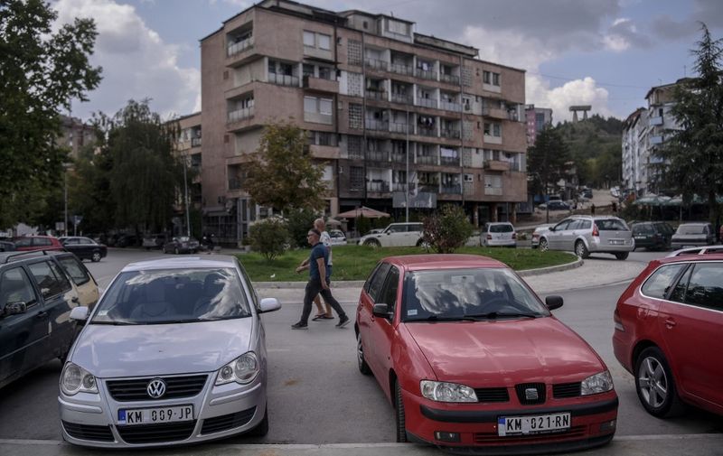 Serb pedestrians walk past cars in the Serb majority north of Mitrovica, on August 26, 2022. - EU-mediated "crisis management" talks on August 18, 2022, between Serbia and Kosovo failed to quell rising tensions between the Balkan neighbours, but further dialogue will take place, the bloc's diplomatic chief said. (Photo by Armend NIMANI / AFP)