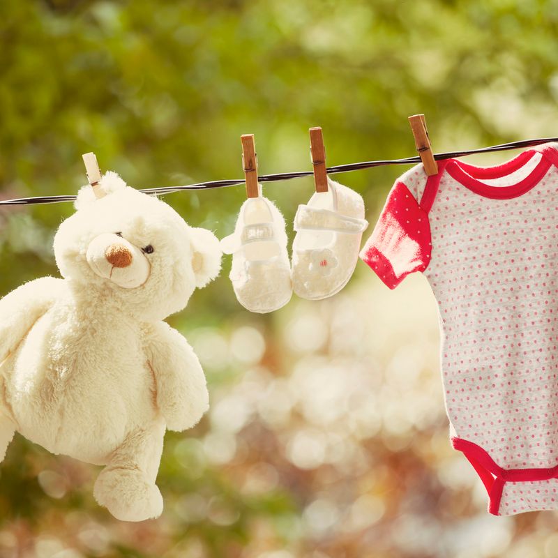Baby clothes and teddy bear hanging on the clothesline - family concept