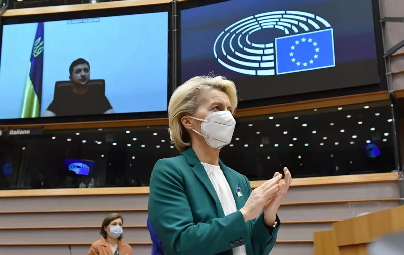 European Commission President Ursula von der Leyen (C) applauds Ukrainian President Volodymyr Zelensky (L) who appears on a screen as he speaks in a video conference during a special plenary session of the European Parliament focused on the Russian invasion of Ukraine at the EU headquarters in Brussels, on March 01, 2022. - The European Commission has opened the door for Ukraine to join the EU, but this is not for tomorrow, despite Kiev's request for a special procedure to integrate the country "without delay". (Photo by JOHN THYS / AFP)