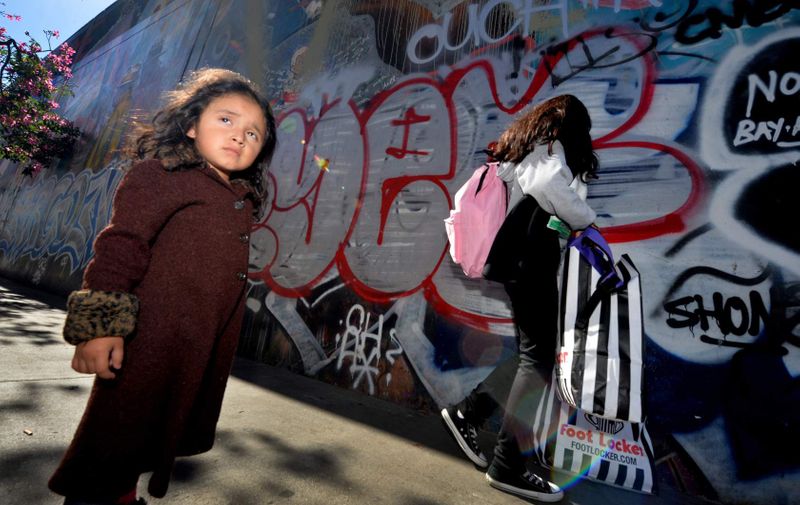 Three year old Saria Amaya (L) waits with her mother after receiving shoes and school supplies during a charity event to help more than 4,000 underprivileged children at the Fred Jordan Mission in the Skid Row area of Los Angeles on October 2, 2014. Skid Row reportedly contains one of the largest populations of homeless people in the United States.                  AFP PHOTO/Mark RALSTON        (Photo credit should read MARK RALSTON/AFP/Getty Images)