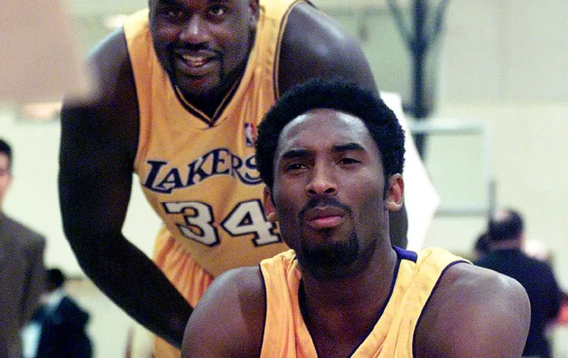 Los Angeles Lakers Shaquille O'Neal (L) looks over the shoulder of teammate Kobe Bryant as he conducts a television interview 02 October 2000 during media day at the Laker practice facility in El Segundo, CA.      AFP PHOTO/Scott NELSON (Photo by - / AFP)