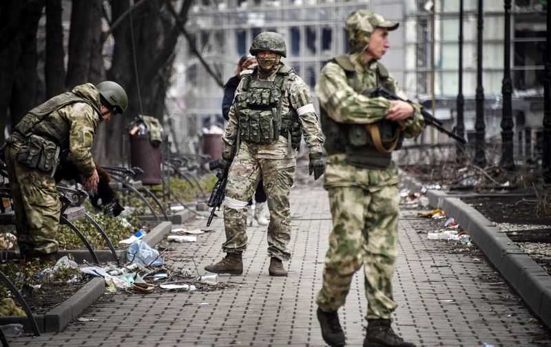 Russian soldiers walks along a street in Mariupol on April 12, 2022, as Russian troops intensify a campaign to take the strategic port city, part of an anticipated massive onslaught across eastern Ukraine, while Russia's President makes a defiant case for the war on Russia's neighbour. (Photo by Alexander NEMENOV / AFP)