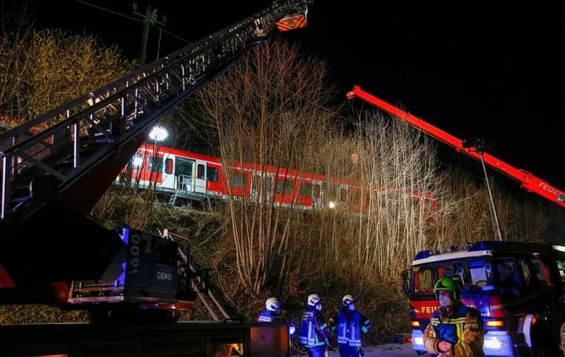 Members of the emergency services work at the scene of an S-bahn commuter train accident where one person was killed and more than ten injured in a collision between two suburban trains at Schaeftlarn in a district of Munich, southern Germany on Februray 14, 2022. (Photo by MICHAELA REHLE / AFP)