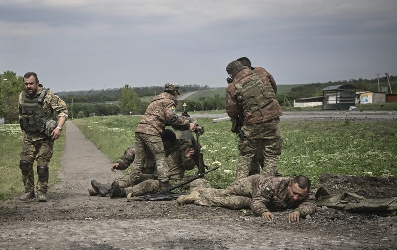 Ukrainian servicemen assist their comrades not far from the frontline in the eastern Ukrainian region of Donbas, on May 21, 2022. (Photo by AFP)