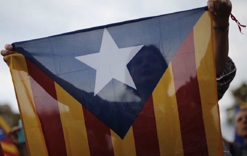 A protester waves a pro-independence Catalan Estelada flag during a demonstration in Barcelona on October 21, 2017 in support of two separatist leaders Jordi Sanchez and Jordi Cuixart, who have been detained pending an investigation into sedition charges.
Spain announced that it will move to dismiss Catalonia's separatist government and call fresh elections in the semi-autonomous region in a bid to stop its leaders from declaring independence. / AFP PHOTO / PAU BARRENA