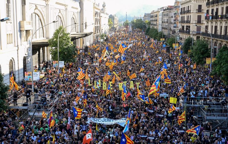 Demonstrators hold letters reading "Freedom" and wave Catalan pro-independence "Estelada" flags during a protest marking the "Diada", the national day of Catalonia, in Barcelona on September 11, 2022. - The protest coincides with Catalonia's national day, or "Diada", which commemorates the 1714 fall of Barcelona in the War of the Spanish Succession and the region's subsequent loss of institutions. (Photo by Josep LAGO / AFP)