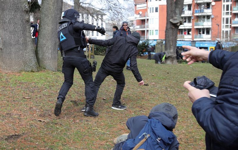 A protestor and a policeman clash on the sidelines of a demonstration demanding the compliance of basic rights and an end of the restrictive coronavirus measures in Kassel, central Germany, on March 20, 2021. - Several thousand critics and so-called 'Querdenker' from all over Germany were expected to take part in the protest organised by the group 'Freie Buerger Kassel'. (Photo by ARMANDO BABANI / AFP)