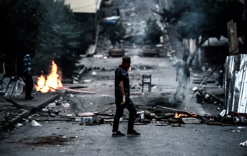 A left-wing protester waits in front of a barricade during clashes with Turkish riot police in the district of Gazi in Istanbul, on July 26, 2015. A Turkish policeman was killed on July 26, 2015 during clashes with protesters in the flashpoint Istanbul district of Gazi which have raged for the last three days following the death of a leftist activist during raids by the security forces. Turkey has launched a two-pronged "anti-terror" cross-border offensive against Islamic State (IS) jihadists and Kurdistan Workers Party (PKK) militants after a wave of violence in the country, pounding their positions with air strikes and artillery. But the expansion of the campaign to include not just IS targets in Syria but PKK rebels in neighbouring northern Iraq -- themselves bitterly opposed to the jihadists -- has put in jeopardy a truce with the Kurdish militants that has largely held since 2013. AFP PHOTO / OZAN KOSE (Photo by OZAN KOSE / AFP)
