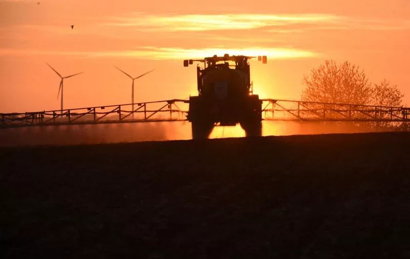 The suns rises as a French farmer sprays glyphosate herbicide "Roundup 720" made by agrochemical giant Monsanto, at the rate of 432 grams per hectare, in Piace, northwestern France, in a corn field, near a wind farm on April 23, 2021. Two root weedkillers, Duald Gold and Spectrum at 1 liter per hectare and a vegetable oil at 0.05 liter per 100 liters are combined with Glyphosate and 36 liters of water per hectare. The plant cover was destroyed mechanically, with a "Duro compil", which in a single pass crushes the stems, so that they disintegrate in contact with the soil, the air and the test. The corn was sown, then rolled. Experimentation with this technique makes it possible to get out of glyphosate. (Photo by JEAN-FRANCOIS MONIER / AFP)